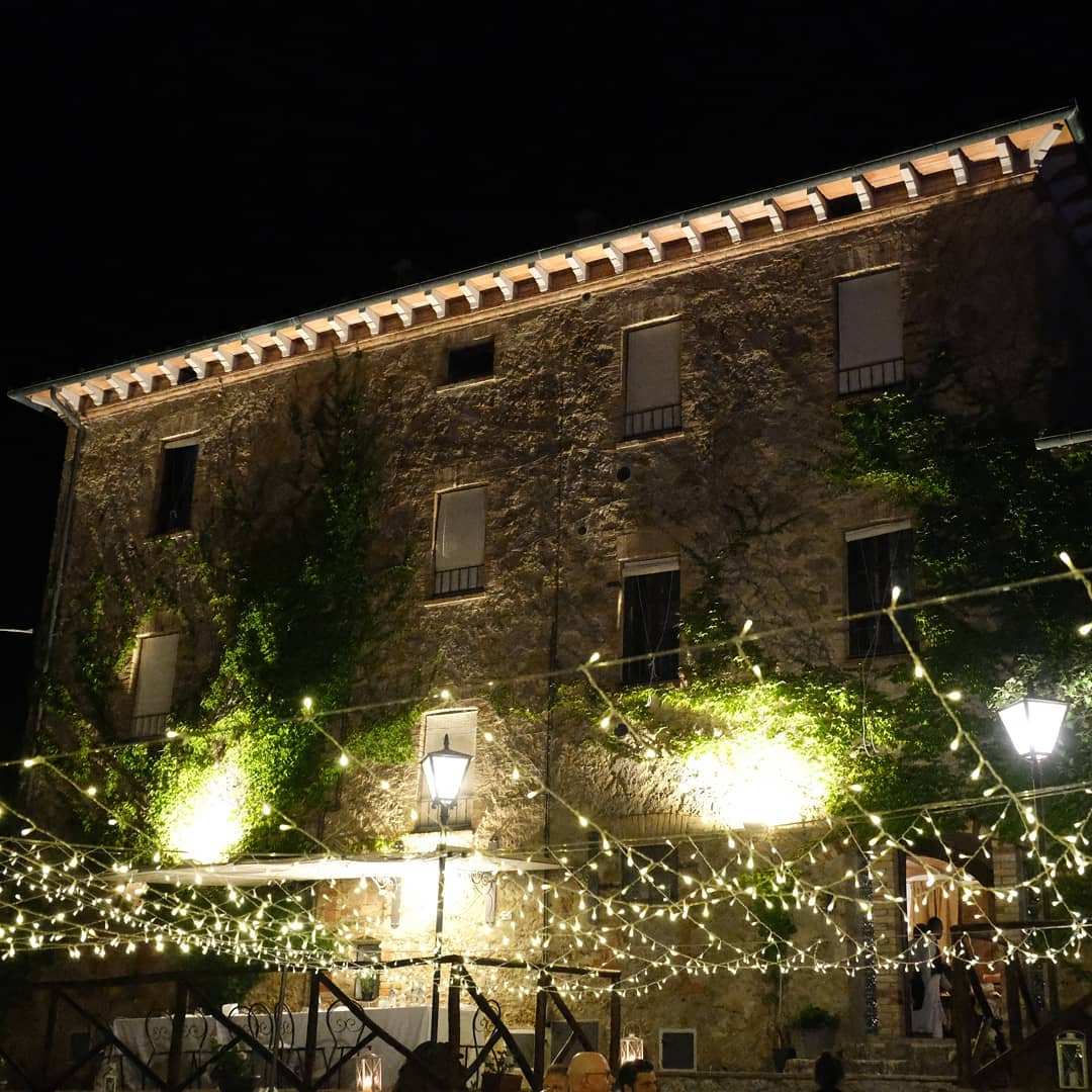 Facciata in pietra di Villa Le Querce illuminata di sera